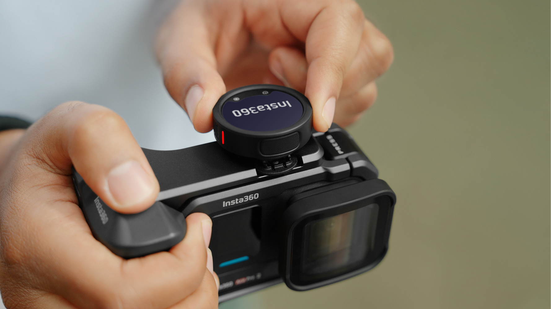 Insta360 Mic Pro, with "Insta360" displayed on its customizable e-ink display, linked up to the cold shoe of an Insta360 Ace Pro 2's Xplorer Grip Pro Kit.
